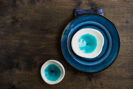 Rustic table setting with ceramic plates and modern cutlery on dark background with copy spaceの写真素材