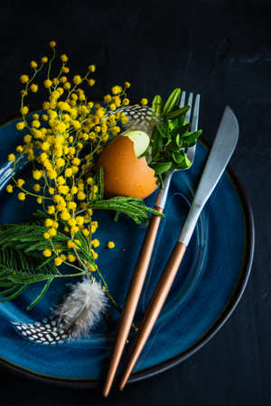 Festive table setting for Easter holiday dinner decorated with flowers and eggs