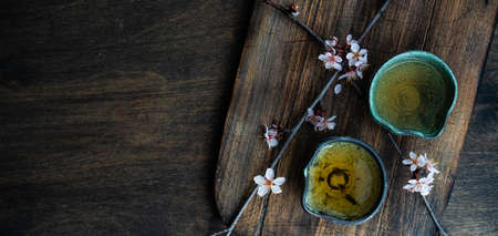 Asian style green tea set and blooming peach tree branch on wooden table with copy spaceの写真素材