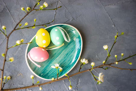 Easter table setting with colored eggs, spring flowers and stone plate