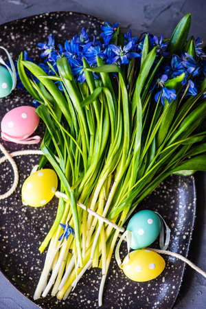 Easter table setting with colored eggs, spring flowers and stone plateの写真素材