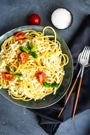 Italian pasta with cheese, tomatoes and herbs on grey background with copy spaceの写真素材