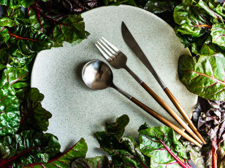 Table setting and fresh spinach leaves as abackground for stone plate