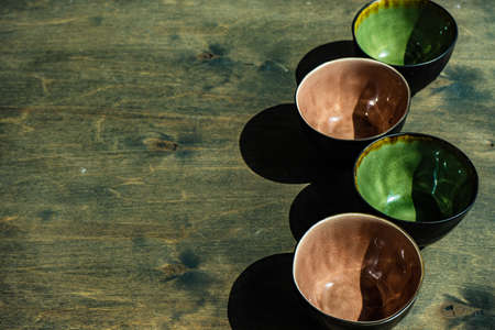 Collecton of empry ceramic bowls on rustic background in sunny day with shadowsの写真素材
