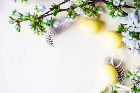 Easter holiday card concept with yellow colored eggs and boxwood on pastel yellow backgroundの写真素材