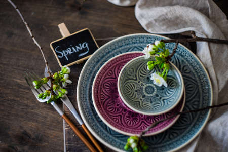Spring table setting in rustic style decorated with cherry bloom tree branches