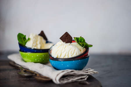 Dessert concept with vanilla ice cream decorated with fresh mint leaves and chocolate pieces