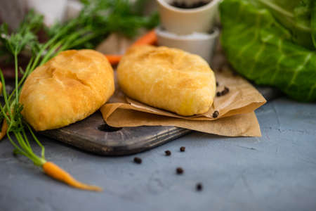 Traditional pies with cabbege and carrot on rustic background