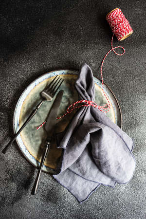 Modern metal cutlery and grey ceramic plate on dark background with copy spaceの写真素材