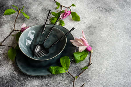 Spring table setting with magnolia blossom on grey concrete background with copy space
