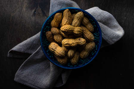 Bowl full of peanuts on dark wooden table with copy spaceの写真素材