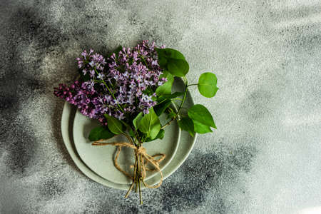 Spring table setting with beautiful lilac flowers on grey concrete background with copy space