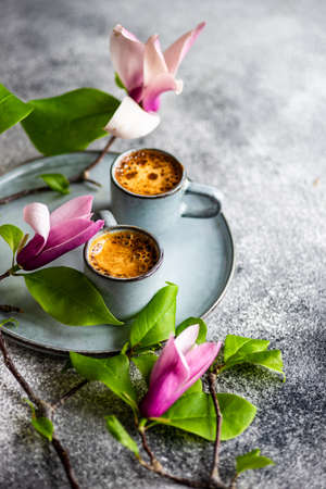 Cup of coffee and magnolia flowers on concrete background with copy space as a morning breakfast...