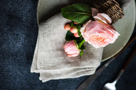 Festive table setting with beautiful roses, modern plates and cutlery on rustic grey background with copy spaceの写真素材