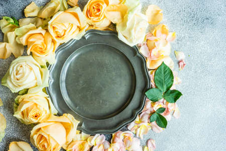 Festive table setting with beautiful roses, modern plates and cutlery on rustic grey background with copy spaceの写真素材