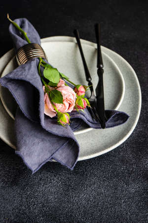 Festive table setting with beautiful roses, modern plates and cutlery on rustic grey background with copy spaceの写真素材