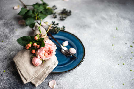 Festive table setting with beautiful roses, modern plates and cutlery on rustic grey background with copy spaceの写真素材