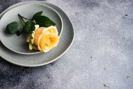 Festive table setting with beautiful roses, modern plates and cutlery on rustic grey background with copy spaceの写真素材