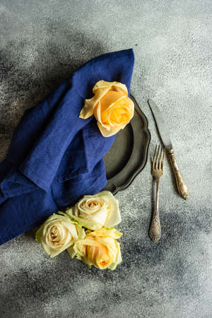 Festive table setting with beautiful roses, modern plates and cutlery on rustic grey background with copy spaceの写真素材