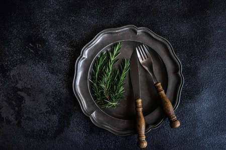 Table setting with fresh rosemary on dark stone table with copy space