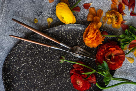 Rustic table setting with ranunculus flowers on concrete background with copy spaceの写真素材