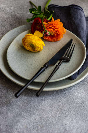 Rustic table setting with ranunculus flowers on concrete background with copy space