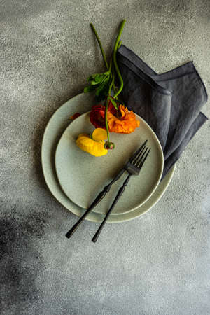 Rustic table setting with ranunculus flowers on concrete background with copy space