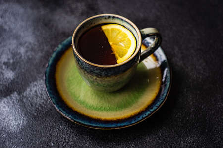 Tea time concept with cup of tea with lemon on dark concrete background with copy spaceの写真素材