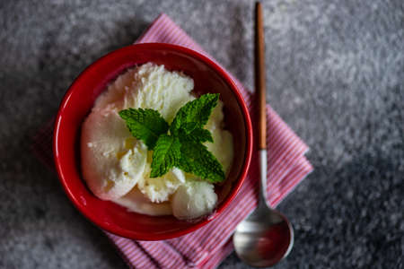 Dessert concept with vanilla ice cream decorated with fresh mint leaves and chocolate pieces