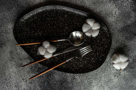 Minimalistic table setting with ceramic plate and cutlery on rusty stone background