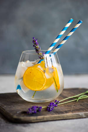 Fresh summer detox drink with lemon and lavender flower on rustic background with copy space