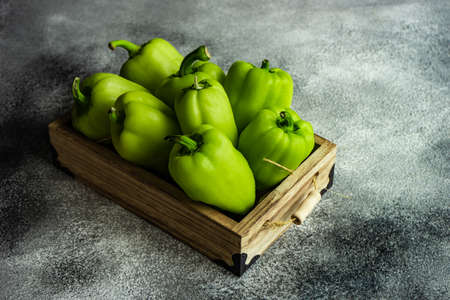 Organic food concept with green bell peppers in a box on rusty backgroundの写真素材