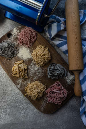 Cooking concept with italian homemade pasta variety on concrete background with blue pasta machine and napking with copy spaceの写真素材