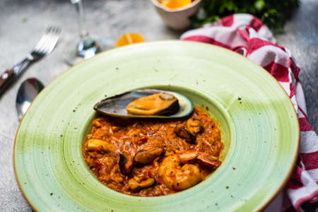 Italian risotto with seafood, served with glass of dry white wine, lemons and salt on concrete background with copy spaceの写真素材