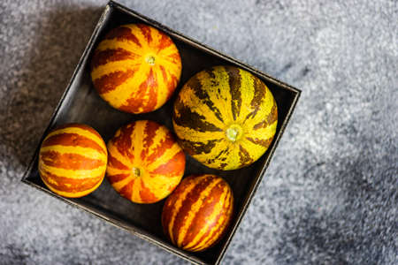 Organic ripe mini melons on grey concrete background with copy space
