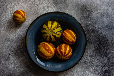 Organic ripe mini melons on grey concrete background with copy space