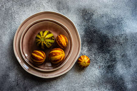Organic ripe mini melons on grey concrete background with copy space
