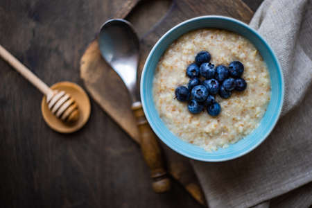 Bowl with oatmeal and blueberries on rustic wooden table as a healthy breakfast conceptの写真素材