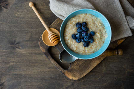 Bowl with oatmeal and blueberries on rustic wooden table as a healthy breakfast conceptの写真素材