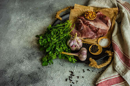 Cooking concept with meat, spices and herbs on stone table with copy spaceの写真素材