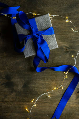 Christmas gift concept with bright ribbon and fir tree on wooden background with copy spaceの写真素材
