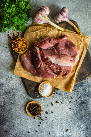 Cooking concept with meat, spices and herbs on stone table with copy spaceの写真素材