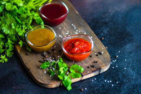 Traditional georgian sauces like tomato satsebeli, yellow and red tkemali with ingredients on stone...