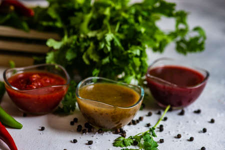 Traditional georgian sauces like tomato satsebeli, yellow and red tkemali with ingredients on stone...
