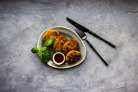 Served pork cutlets with fresh basil herb and sauce on stone background with copy spaceの写真素材