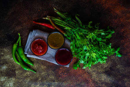 Traditional georgian sauces like tomato satsebeli, yellow and red tkemali with ingredients on stone...