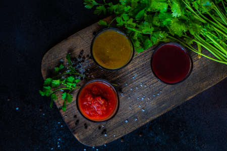 Traditional georgian sauces like tomato satsebeli, yellow and red tkemali with ingredients on stone background with copy spaceの写真素材