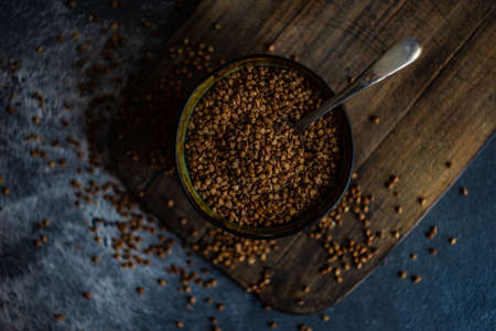 Organic raw buckwheat seeds in a rustic bowl on stone background with copyspace