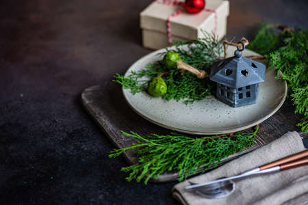 Rustic table setting for festive holiday Christmas dinner with gift box, fir tree and decor on stone...