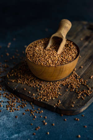 Organic raw buckwheat seeds in a rustic bowl on stone background with copyspaceの写真素材